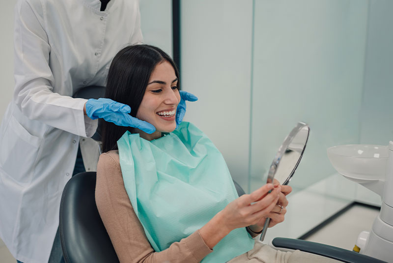 dental implant patient smiling brightly looking at the handheld mirror