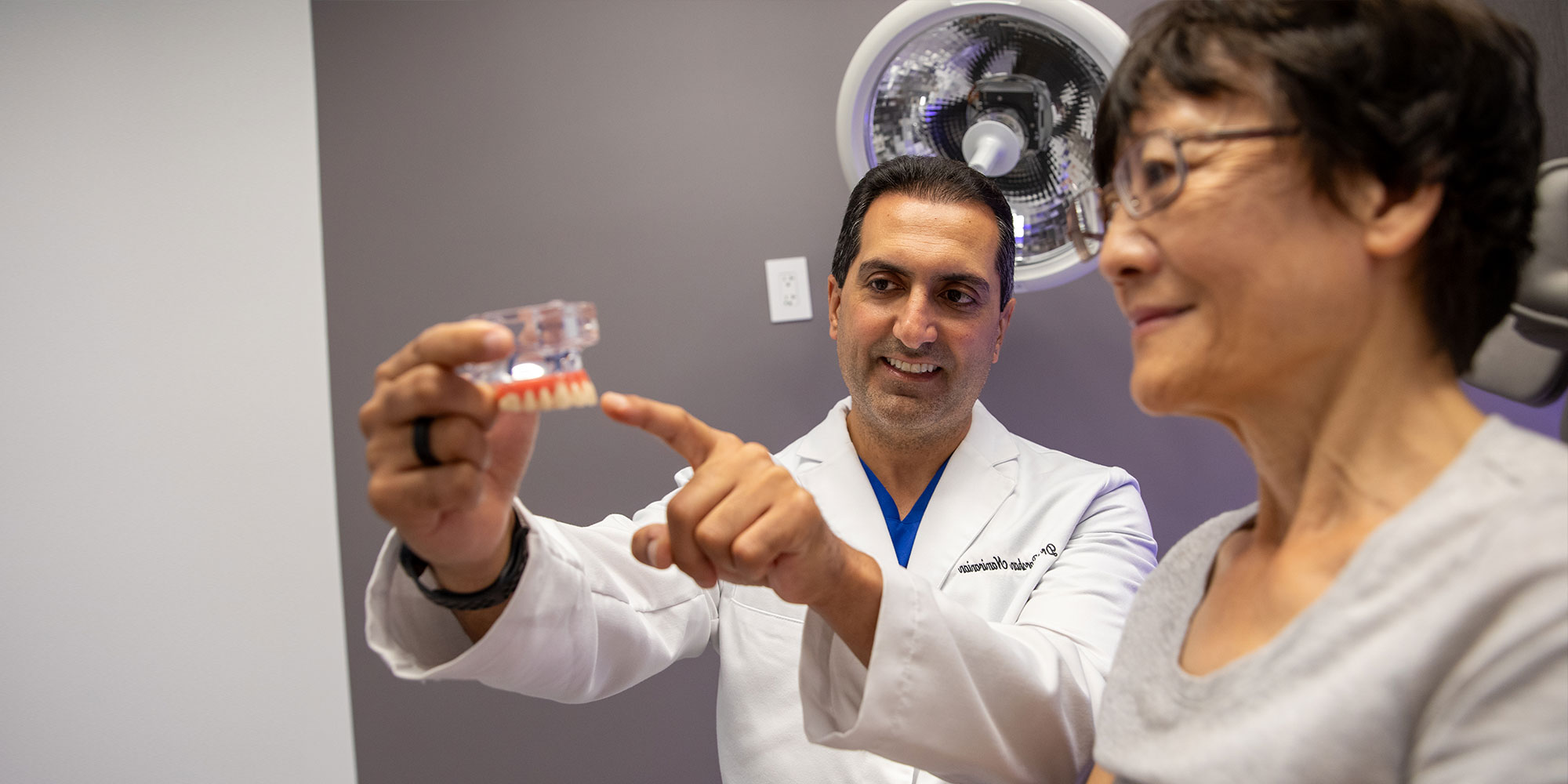patient and doctor smiling while examining full arch model