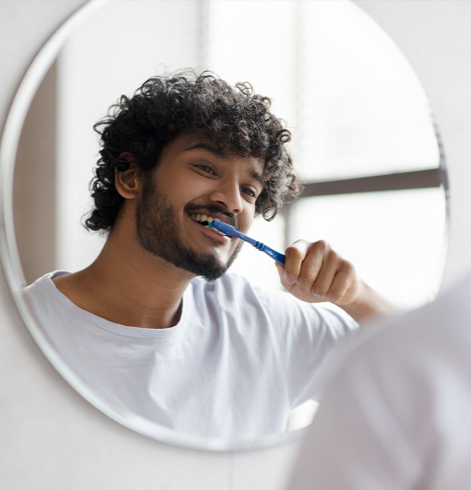 young male brushing their teeth in the bathroom