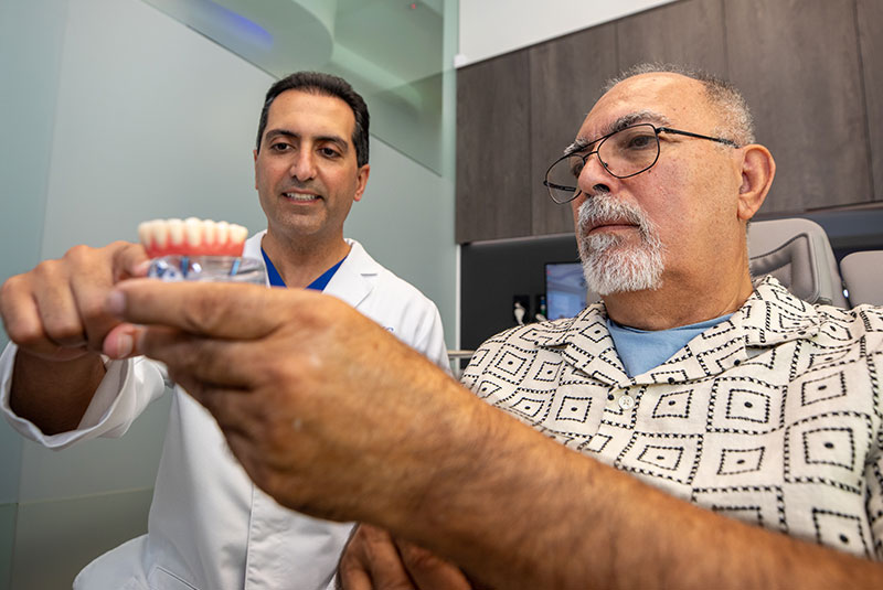doctor and patient going over dental procedure information with full arch model