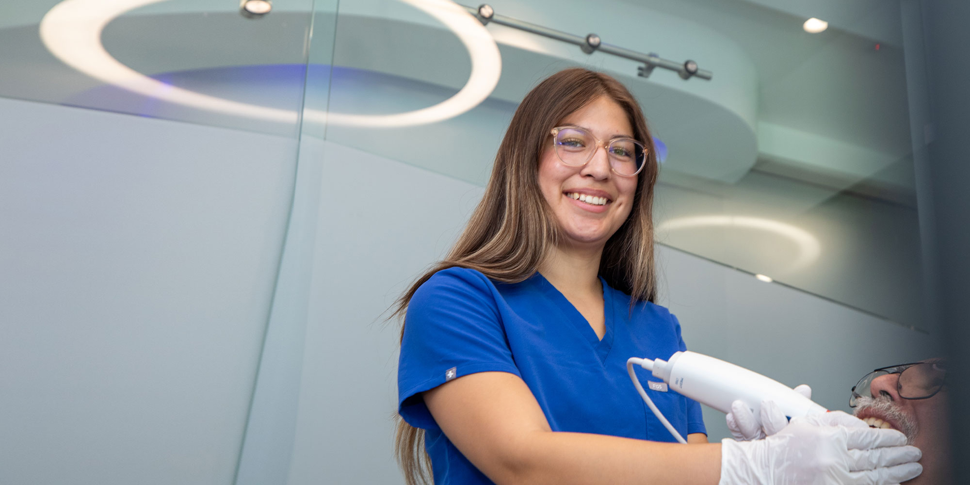 staff member smiling brightly and examining dental patient